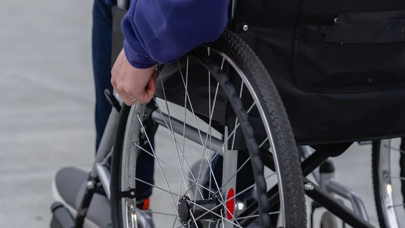 A wheelchair user outdoors, seen from behind.
