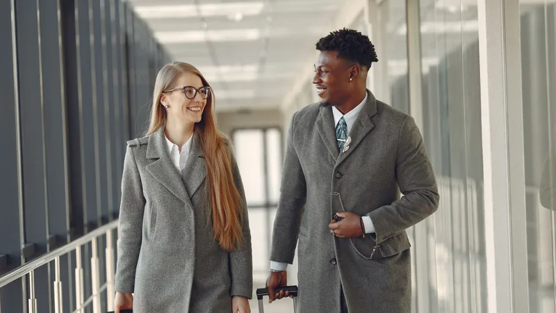 Two business travellers walking through an airport with luggage.